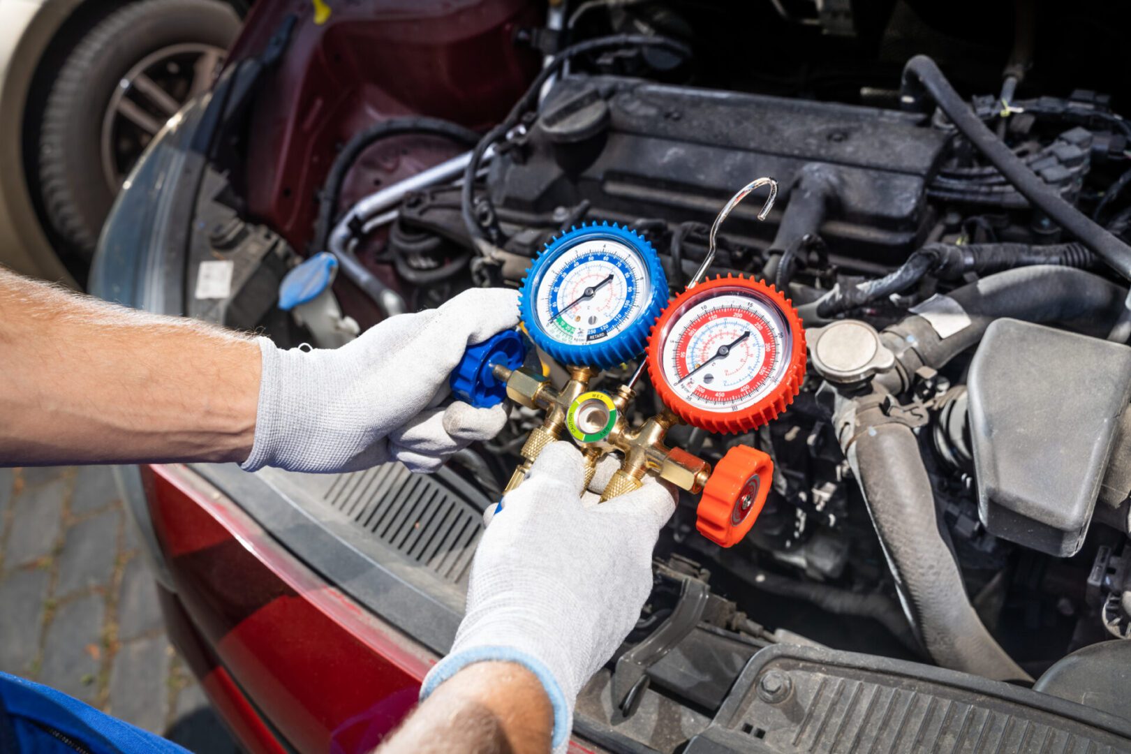 Hands using AC pressure gauges on car